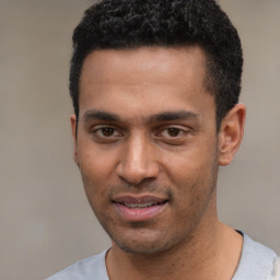 Joyful black young-adult male with short  black hair and brown eyes