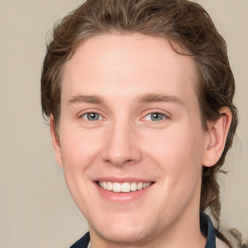 Joyful white young-adult male with medium  brown hair and grey eyes