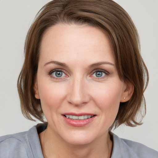 Joyful white young-adult female with medium  brown hair and grey eyes