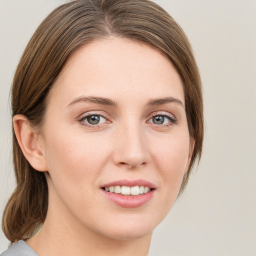 Joyful white young-adult female with medium  brown hair and grey eyes