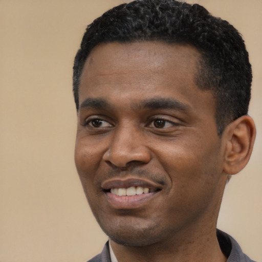 Joyful black young-adult male with short  black hair and brown eyes