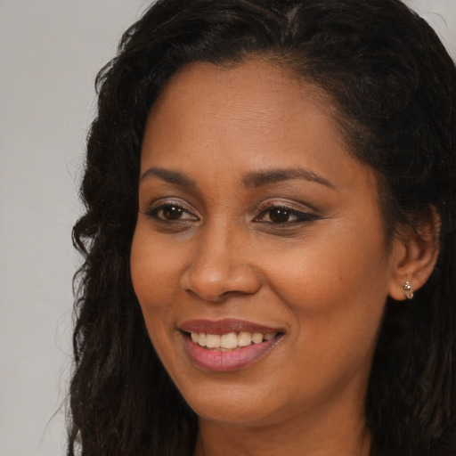 Joyful black young-adult female with long  brown hair and brown eyes