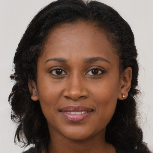 Joyful black young-adult female with long  brown hair and brown eyes