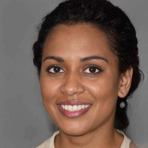 Joyful black young-adult female with long  brown hair and brown eyes
