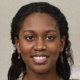 Joyful black young-adult female with long  brown hair and brown eyes