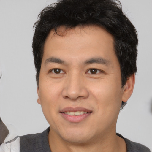 Joyful asian young-adult male with short  black hair and brown eyes