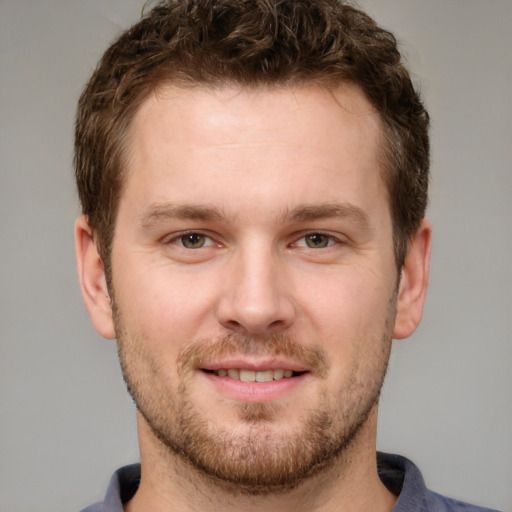 Joyful white young-adult male with short  brown hair and grey eyes