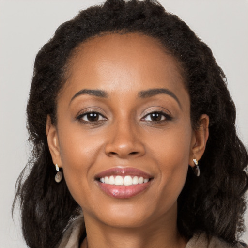 Joyful black young-adult female with long  brown hair and brown eyes