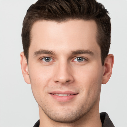 Joyful white young-adult male with short  brown hair and grey eyes