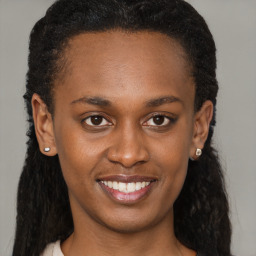 Joyful black young-adult female with long  brown hair and brown eyes