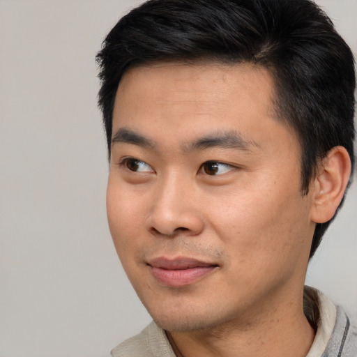 Joyful asian young-adult male with short  black hair and brown eyes