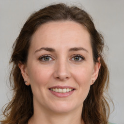 Joyful white young-adult female with long  brown hair and green eyes