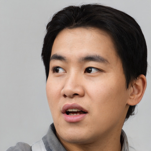 Joyful asian young-adult male with short  black hair and brown eyes