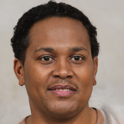 Joyful black young-adult male with short  brown hair and brown eyes
