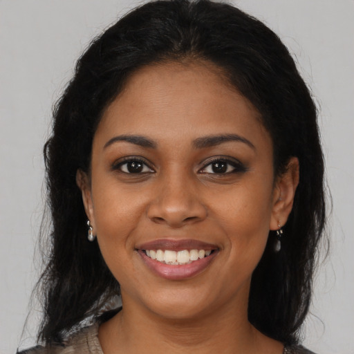 Joyful black young-adult female with long  brown hair and brown eyes