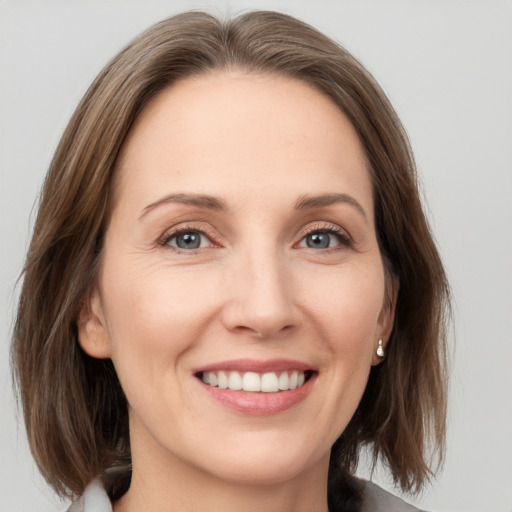 Joyful white young-adult female with medium  brown hair and grey eyes