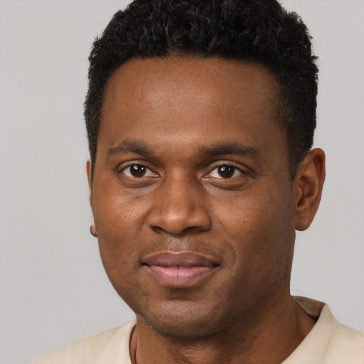 Joyful black young-adult male with short  black hair and brown eyes