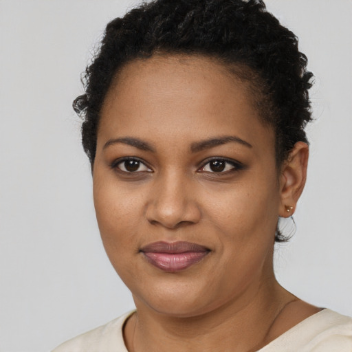 Joyful black young-adult female with short  black hair and brown eyes