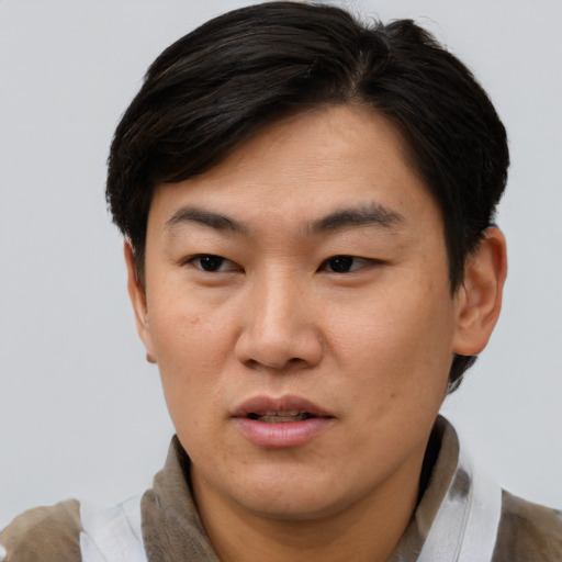 Joyful asian adult male with short  brown hair and brown eyes