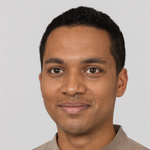 Joyful black young-adult male with short  black hair and brown eyes