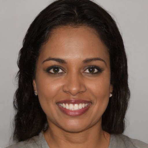 Joyful black young-adult female with long  brown hair and brown eyes