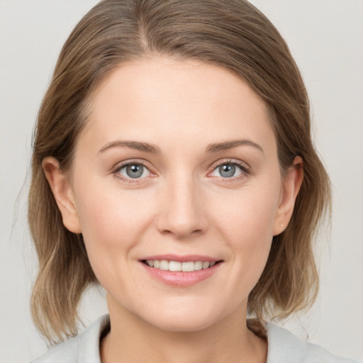 Joyful white young-adult female with medium  brown hair and grey eyes