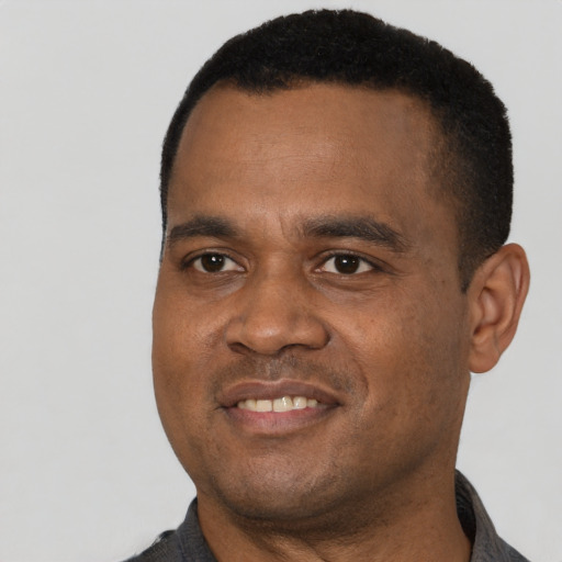 Joyful black young-adult male with short  black hair and brown eyes