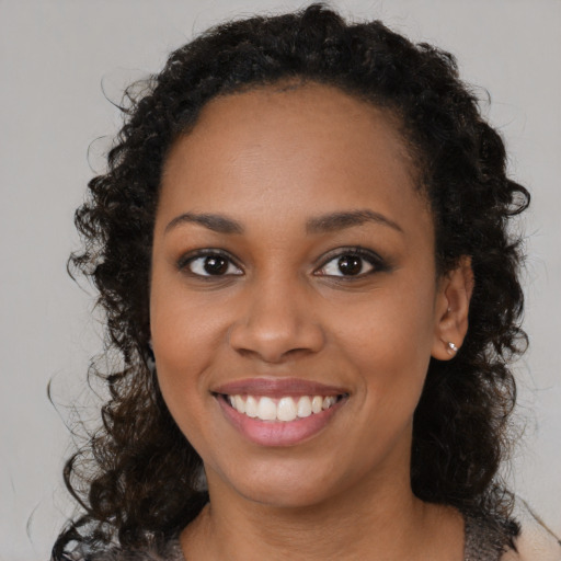 Joyful black young-adult female with long  brown hair and brown eyes