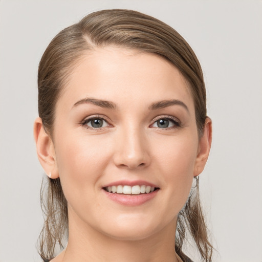 Joyful white young-adult female with medium  brown hair and grey eyes