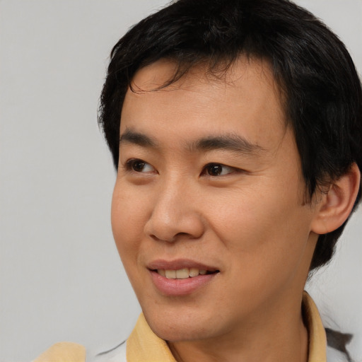 Joyful asian young-adult male with short  brown hair and brown eyes