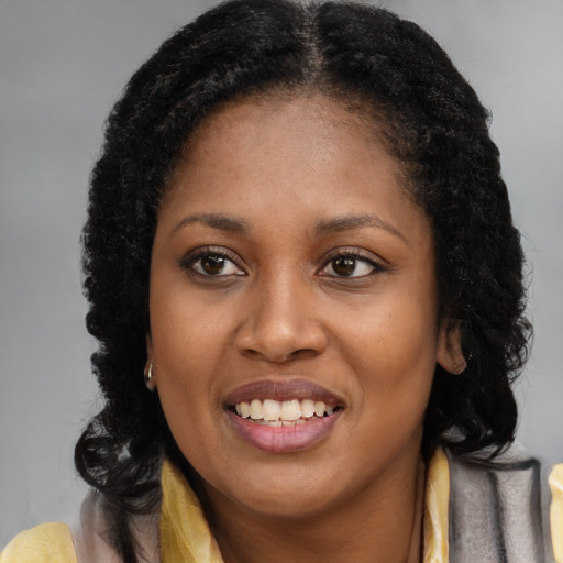 Joyful black young-adult female with long  brown hair and brown eyes