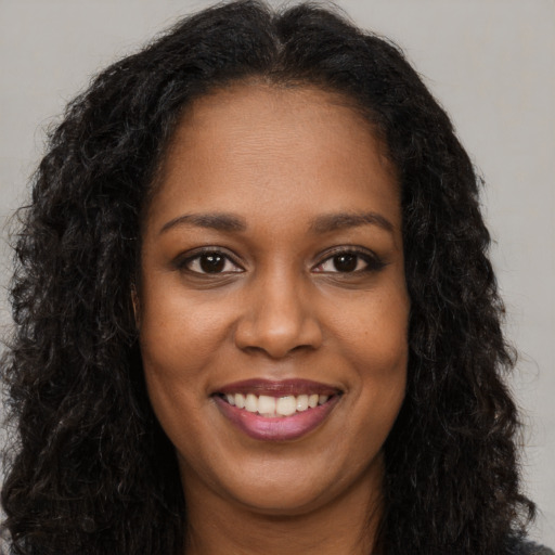 Joyful black young-adult female with long  brown hair and brown eyes