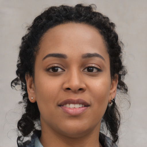 Joyful black young-adult female with long  brown hair and brown eyes