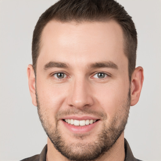 Joyful white young-adult male with short  brown hair and grey eyes