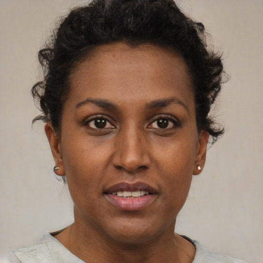Joyful black young-adult female with short  brown hair and brown eyes