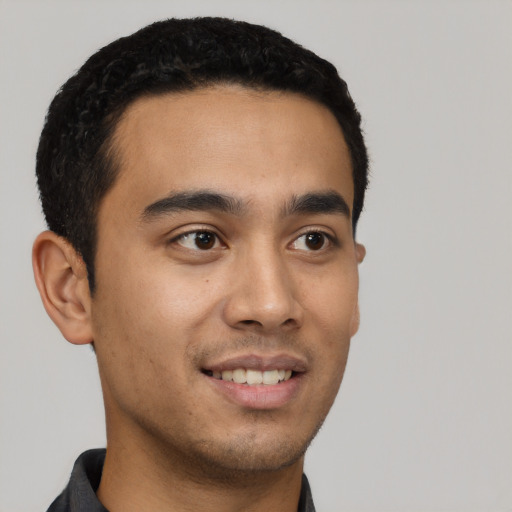 Joyful latino young-adult male with short  black hair and brown eyes