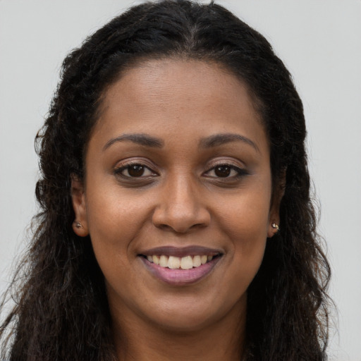Joyful black young-adult female with long  brown hair and brown eyes