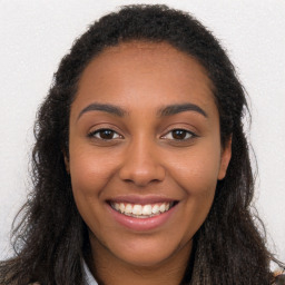 Joyful black young-adult female with long  brown hair and brown eyes