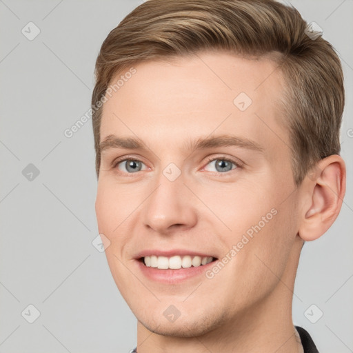 Joyful white young-adult male with short  brown hair and grey eyes