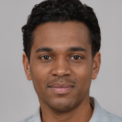 Joyful black young-adult male with short  black hair and brown eyes