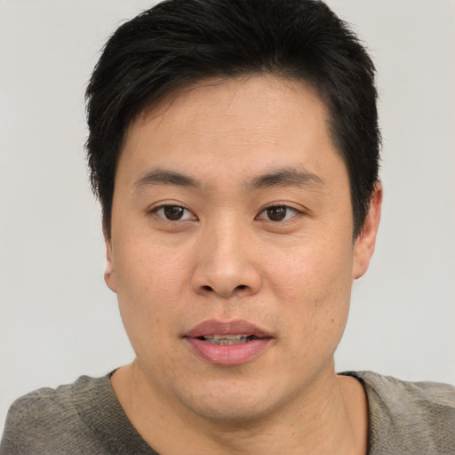 Joyful asian young-adult male with short  brown hair and brown eyes