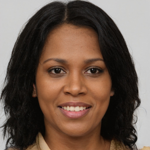 Joyful black adult female with long  brown hair and brown eyes