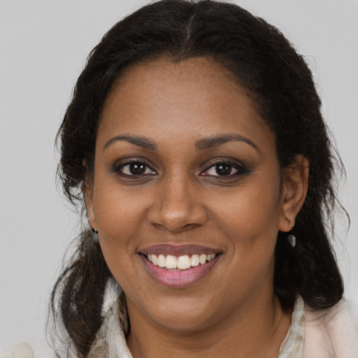Joyful black young-adult female with long  brown hair and brown eyes
