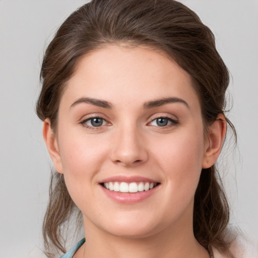 Joyful white young-adult female with medium  brown hair and grey eyes