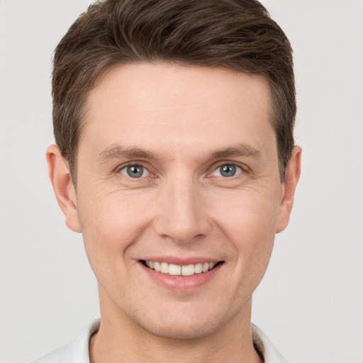 Joyful white young-adult male with short  brown hair and grey eyes