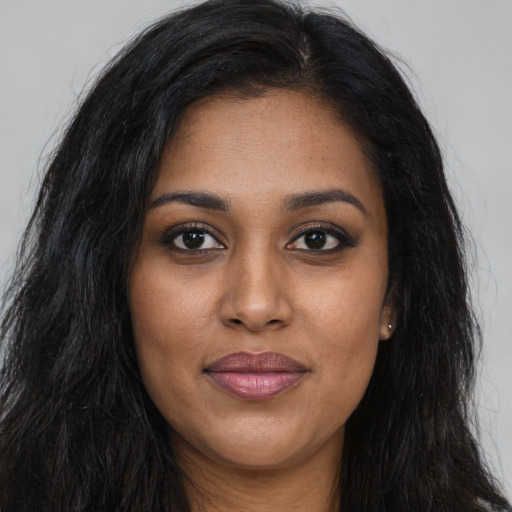 Joyful black young-adult female with long  brown hair and brown eyes