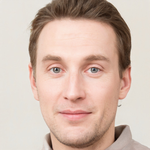 Joyful white young-adult male with short  brown hair and grey eyes