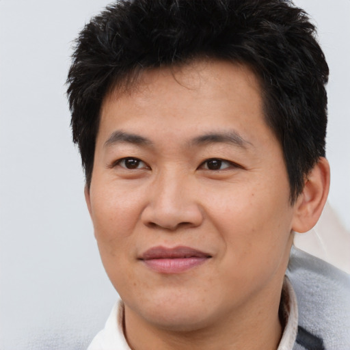 Joyful asian young-adult male with short  brown hair and brown eyes