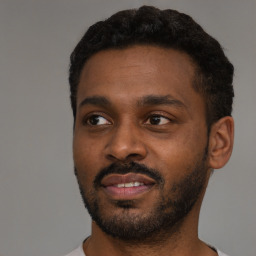 Joyful black young-adult male with short  black hair and brown eyes