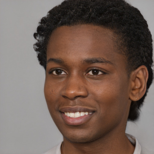 Joyful black young-adult male with short  brown hair and brown eyes